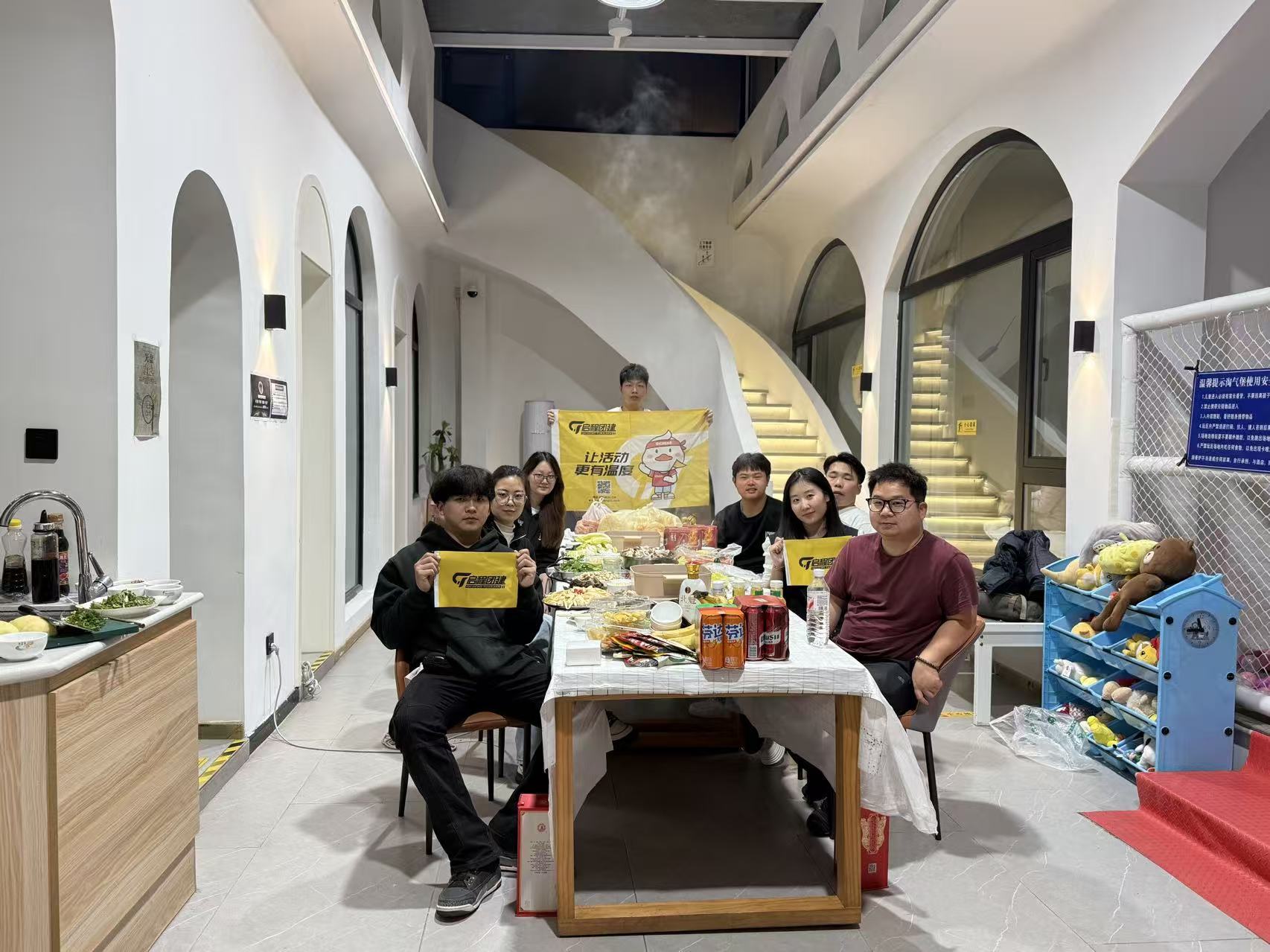 团队成员在聚餐时手持启程品牌旗帜的合影