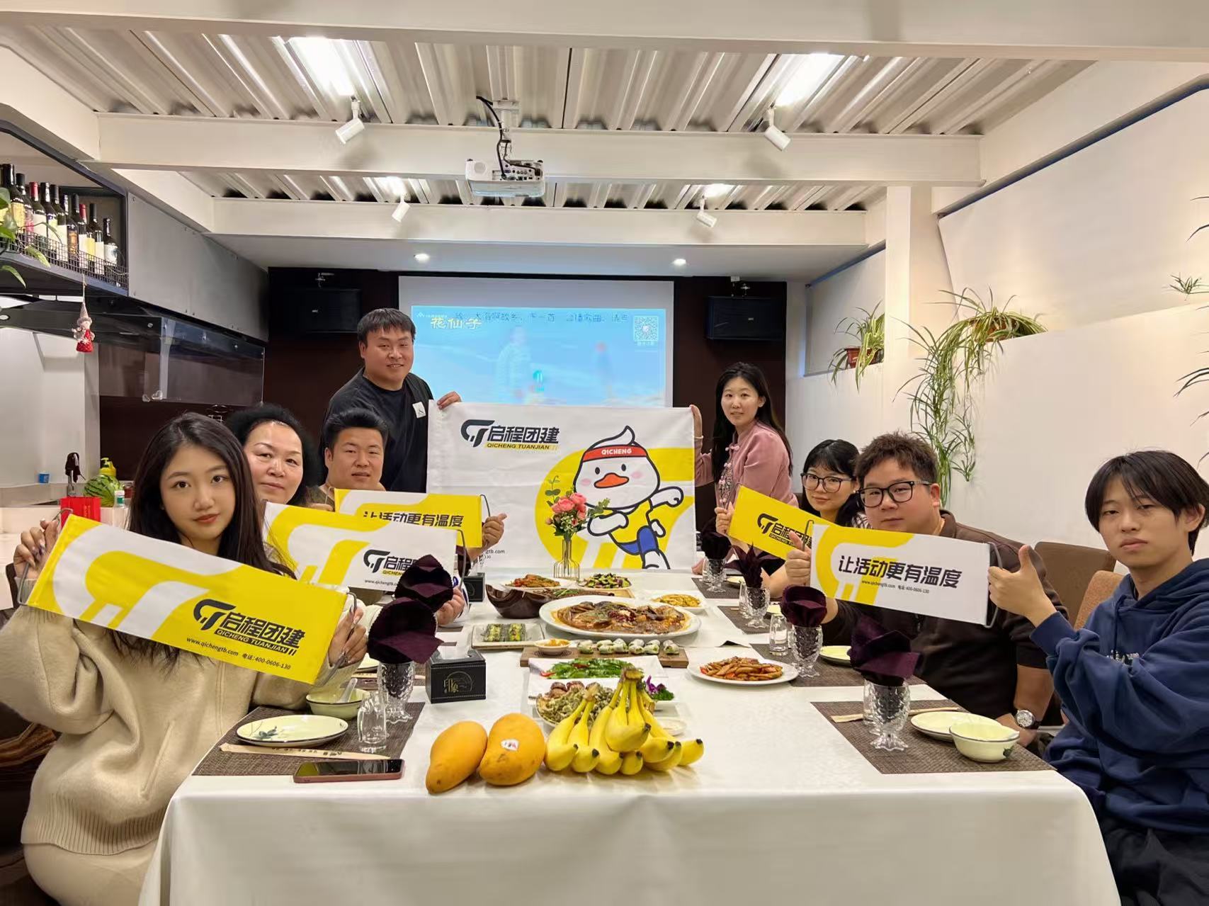 团队成员手持启程品牌旗帜和标语的聚会合影